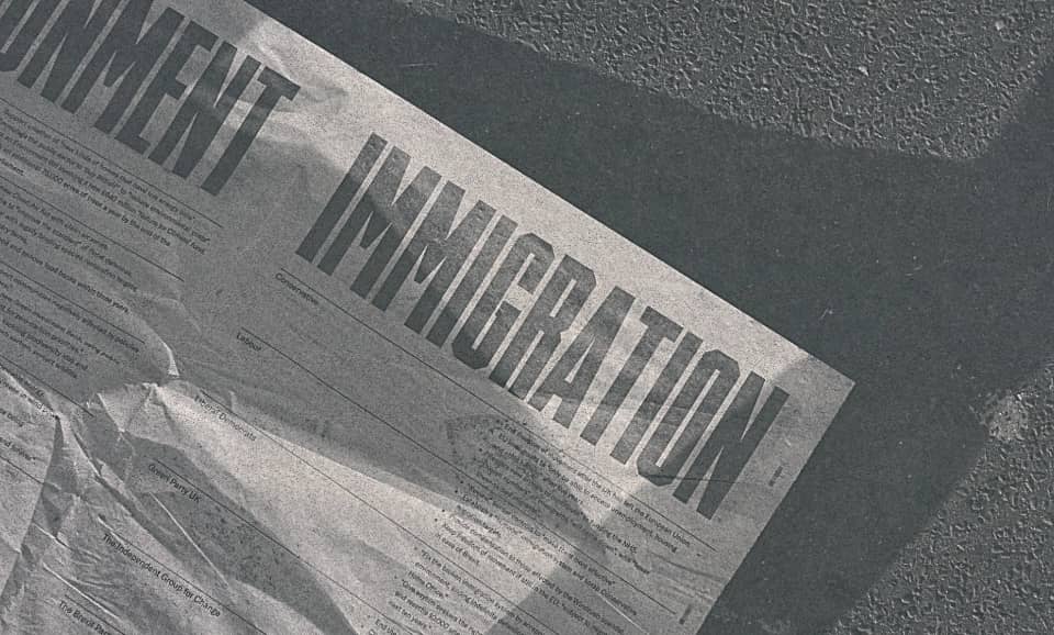 A newspaper's front page is seen laying on the street, with its main title writing "permanent immigration"