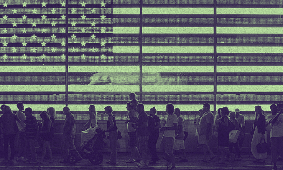 a group of people walking beside a screen with the U.S. flag projected on.