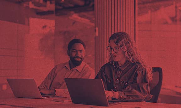 Two people are working on their computers side-by-side.